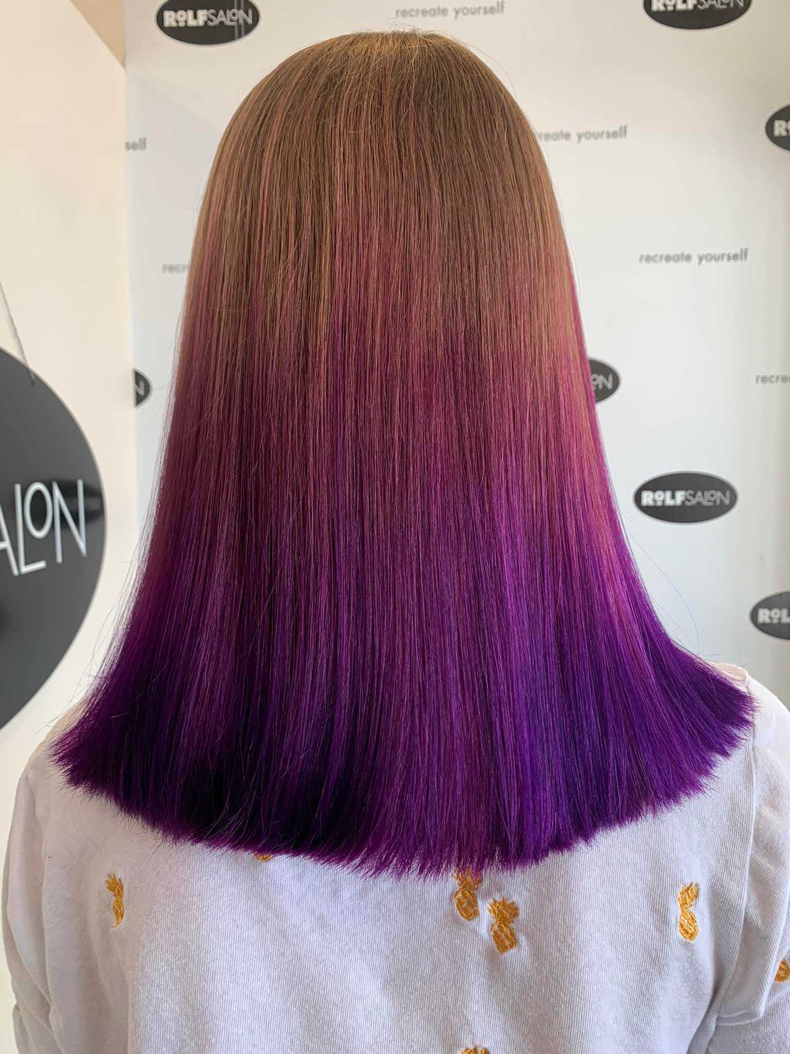 Woman with straight, ombre hair styled from light brown to vibrant purple at a hair salon.