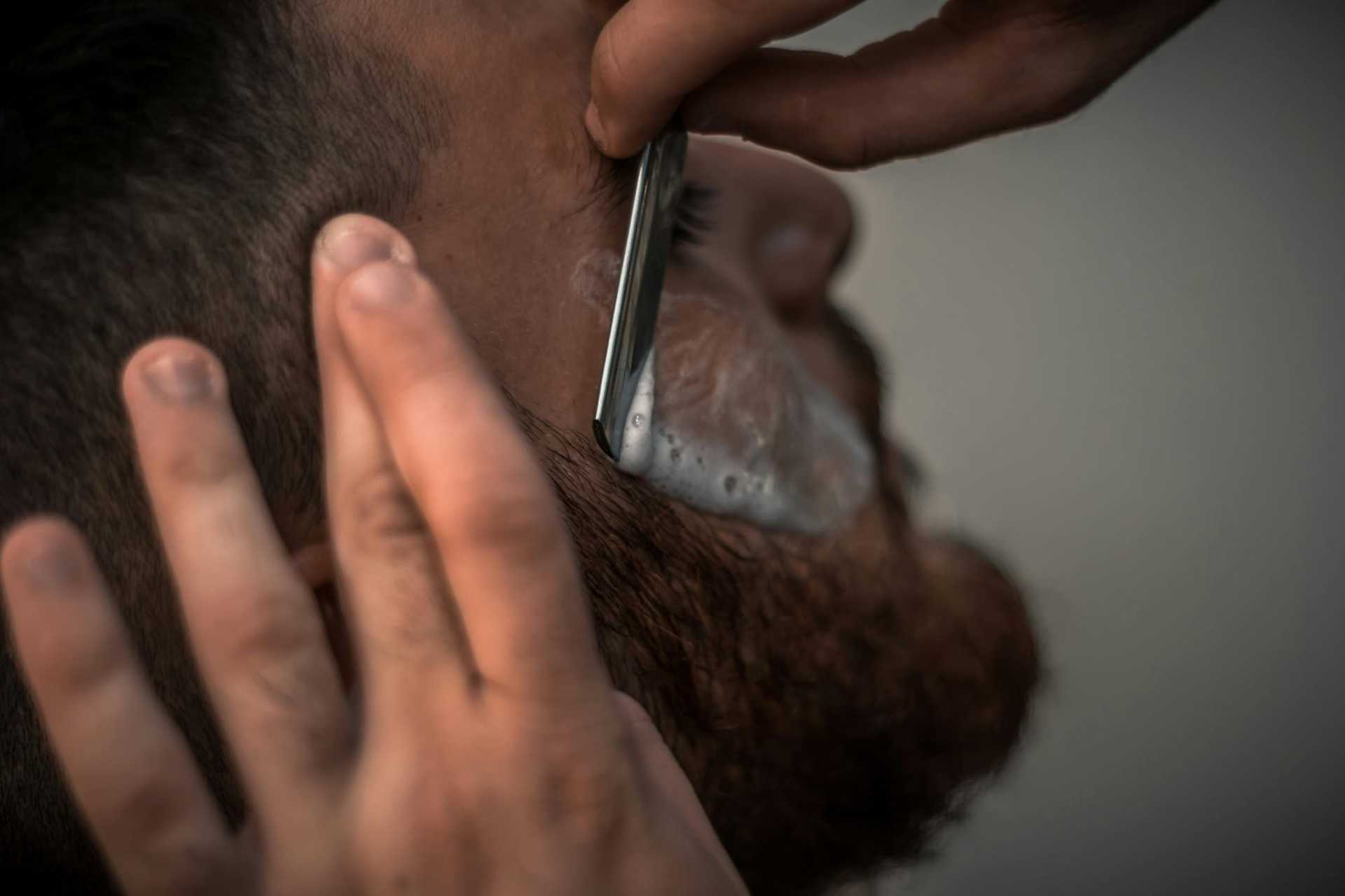 Close-up of a man receiving a traditional wet shave with a straight razor.