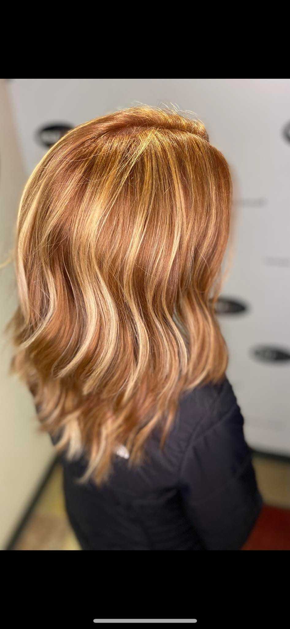 Woman with wavy, shoulder-length, golden brown hair with blonde highlights.